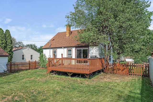back of house with a chimney, roof with shingles, and a deck