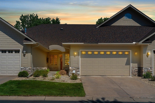 9363 Libby Ln, Eden Prairie, MN 55347 - view of front facade with stone siding, an attached garage, driveway, and roof with shingles