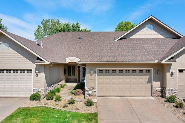9363 Libby Ln, Eden Prairie, MN 55347 - view of front facade with stone siding, an attached garage, and roof with shingles