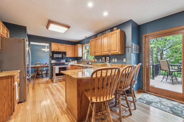 5155 Allen Dr, Woodbury, MN 55129 - kitchen with stainless steel appliances, a peninsula, a sink, light wood-style floors, and light stone counters
