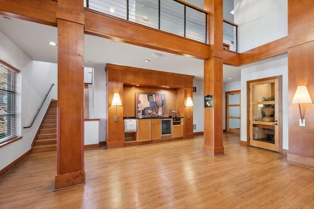 13560 Technology Dr Unit 1207, Eden Prairie, MN 55344 - unfurnished living room with ornate columns, beverage cooler, a towering ceiling, stairway, and baseboards