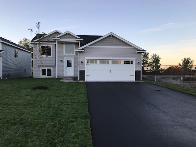 view of front of property featuring asphalt driveway, an attached garage, a front yard, and stone siding
