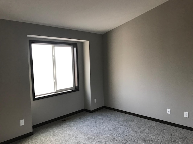carpeted empty room featuring baseboards