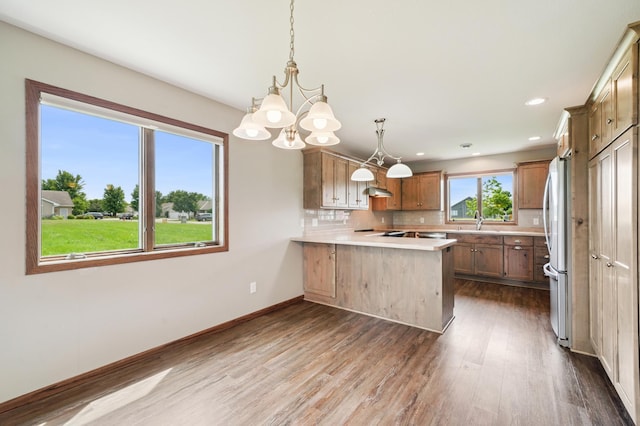 1516 Ranger Dr, Glencoe, MN 55336 - kitchen featuring a peninsula, dark wood-style flooring, light countertops, a chandelier, and backsplash