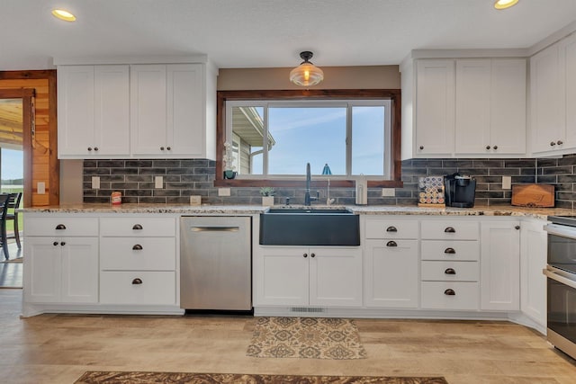 kitchen featuring appliances with stainless steel finishes, a sink, recessed lighting, white cabinets, and tasteful backsplash