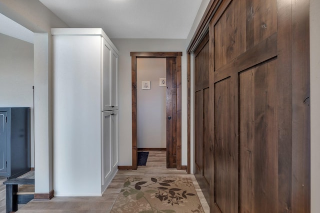 hall featuring light wood-style flooring and baseboards