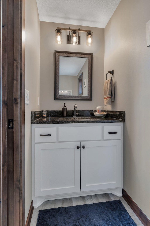 bathroom with baseboards, vanity, and a textured ceiling