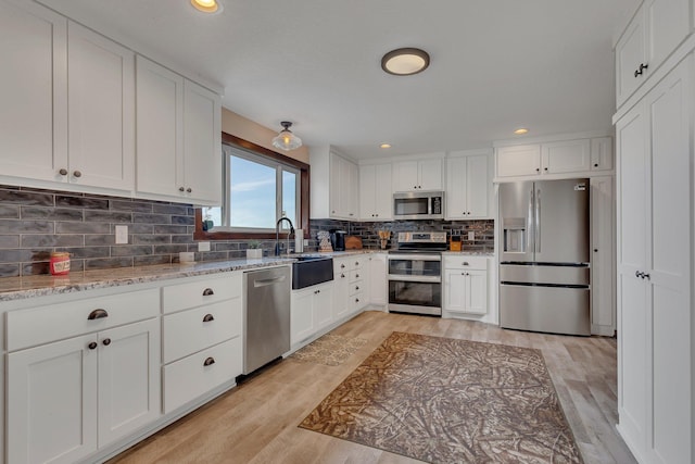 21048 Eagle Dr, Leslie Twp, MN 56360 - kitchen with appliances with stainless steel finishes, light wood-style flooring, a sink, white cabinetry, and recessed lighting