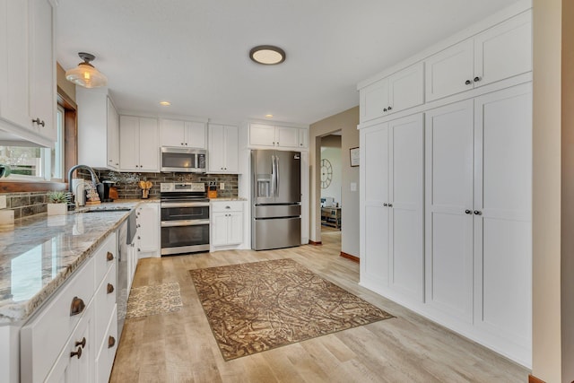 21048 Eagle Dr, Leslie Twp, MN 56360 - kitchen with stainless steel appliances, backsplash, white cabinetry, light stone countertops, and light wood-type flooring