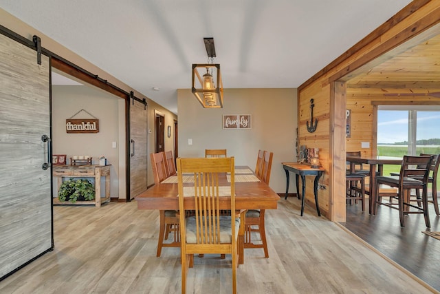 21048 Eagle Dr, Leslie Twp, MN 56360 - dining space featuring a barn door, wood walls, wood finished floors, and baseboards