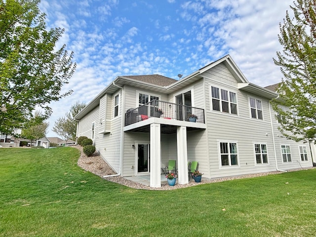 rear view of house featuring a lawn and a balcony
