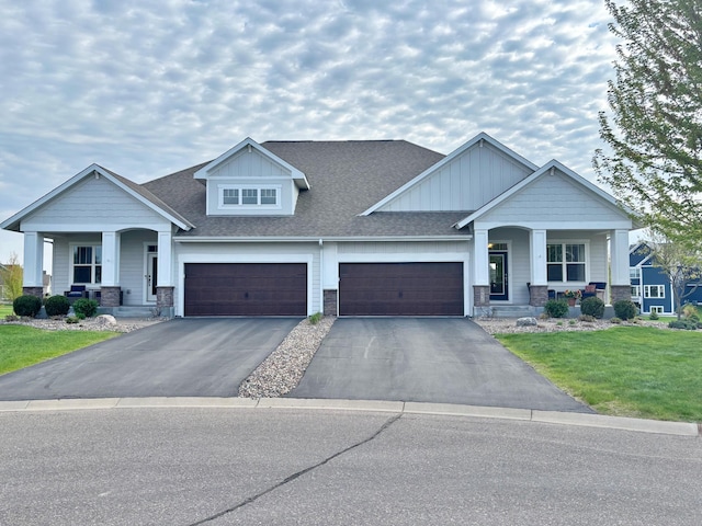 craftsman inspired home featuring a porch, board and batten siding, asphalt driveway, and a front lawn
