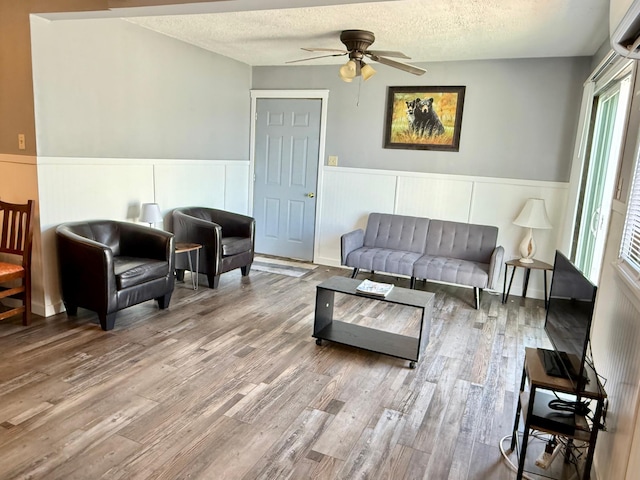 CABIN5 Gruenhagen Rd, Long Lake Twp, WI 54817 - living area featuring a wainscoted wall, a ceiling fan, plenty of natural light, wood finished floors, and a textured ceiling