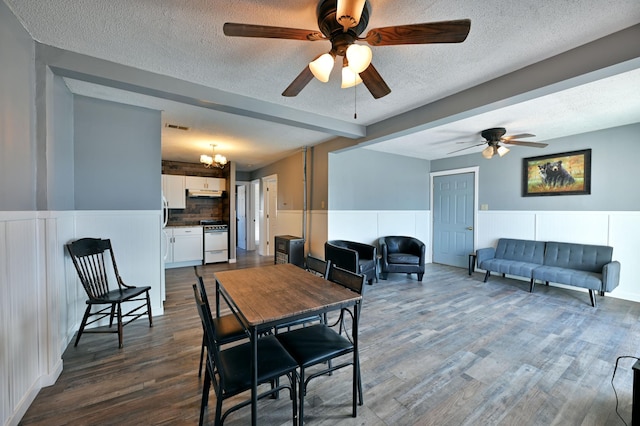CABIN5 Gruenhagen Rd, Long Lake Twp, WI 54817 - dining room featuring a ceiling fan, dark wood-type flooring, a decorative wall, a textured ceiling, and wainscoting