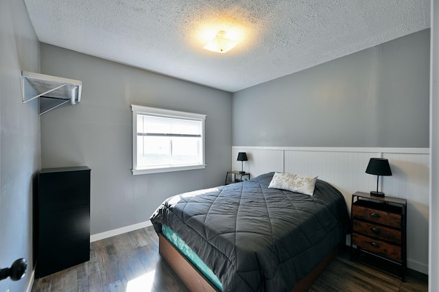 CABIN5 Gruenhagen Rd, Long Lake Twp, WI 54817 - bedroom with a textured ceiling, wood finished floors, a wainscoted wall, and baseboards