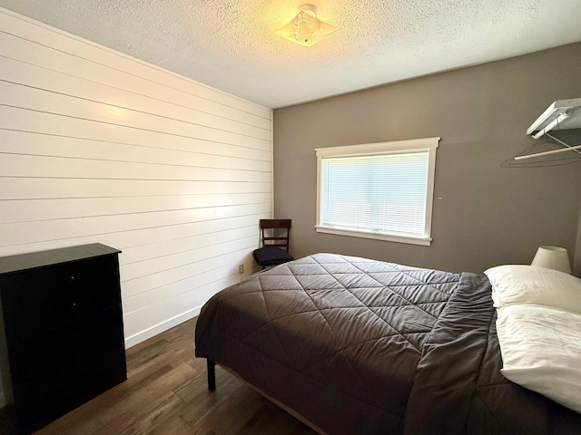 CABIN5 Gruenhagen Rd, Long Lake Twp, WI 54817 - bedroom featuring dark wood-type flooring, a textured ceiling, wood walls, and baseboards