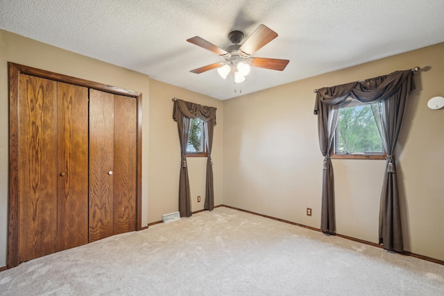 22800 401st Ave, Arlington Twp, MN 55307 - unfurnished bedroom featuring multiple windows, carpet floors, a closet, baseboards, and a textured ceiling