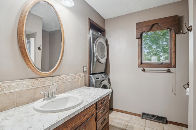 22800 401st Ave, Arlington Twp, MN 55307 - bathroom with stacked washing machine and dryer, vanity, baseboards, and tile patterned floors