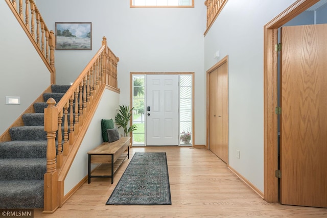 entryway with wood finished floors, stairway, a high ceiling, and baseboards