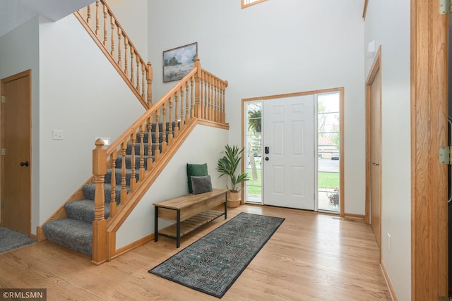 entrance foyer featuring wood finished floors, a high ceiling, stairway, and baseboards
