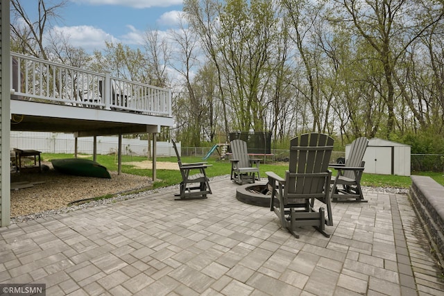 view of patio featuring a storage shed, a trampoline, a playground, an outbuilding, and a deck