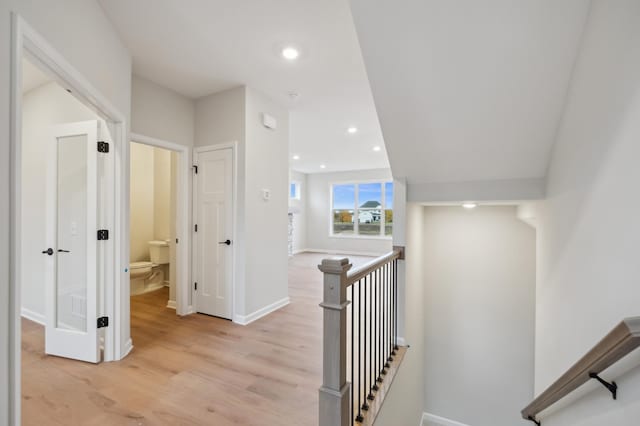 hallway featuring an upstairs landing, light wood finished floors, baseboards, and recessed lighting