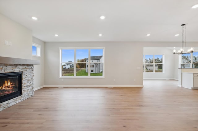 unfurnished living room featuring a fireplace, light wood-style floors, a chandelier, recessed lighting, and baseboards