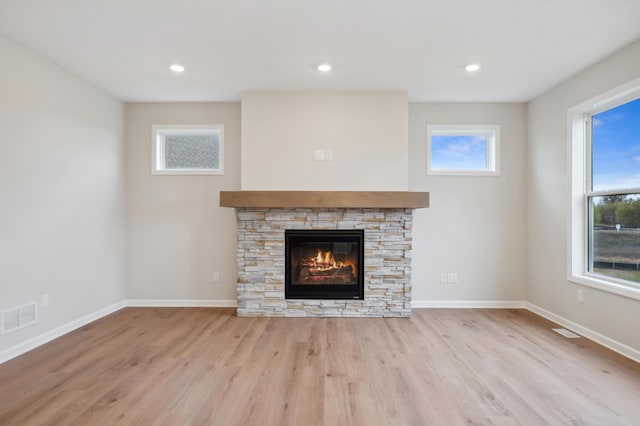 unfurnished living room featuring a stone fireplace, wood finished floors, baseboards, and recessed lighting
