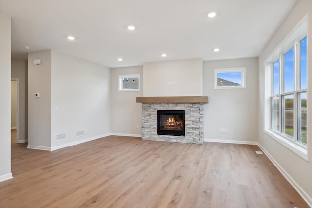 unfurnished living room with light wood-style flooring, a fireplace, plenty of natural light, recessed lighting, and baseboards
