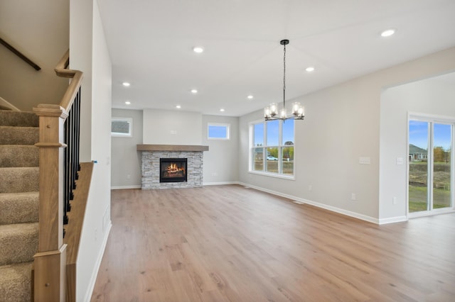 unfurnished living room featuring light wood-style flooring, stairs, baseboards, a stone fireplace, and recessed lighting