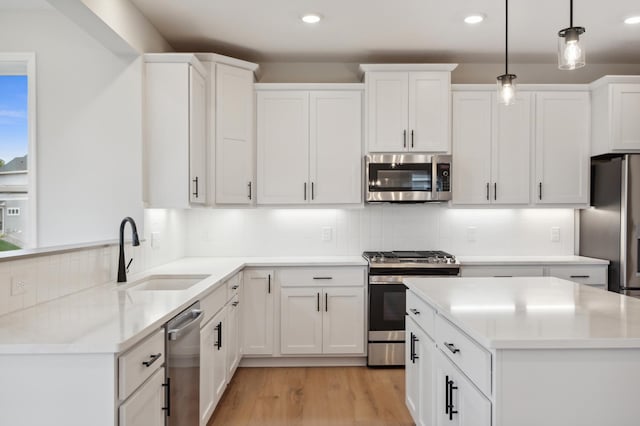 kitchen featuring appliances with stainless steel finishes, a sink, recessed lighting, white cabinets, and tasteful backsplash