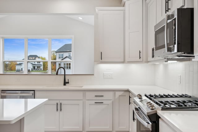 kitchen with stainless steel appliances, a sink, light countertops, tasteful backsplash, and vaulted ceiling