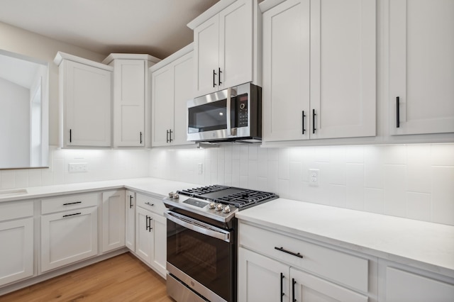 kitchen with appliances with stainless steel finishes, tasteful backsplash, and white cabinetry