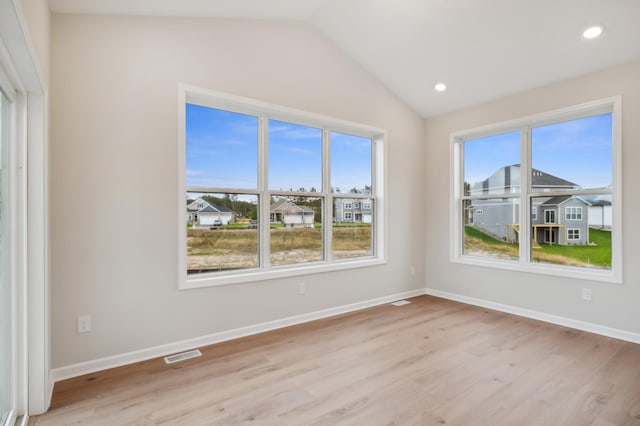 empty room with light wood finished floors, vaulted ceiling, baseboards, recessed lighting, and a residential view