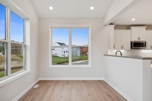 unfurnished dining area featuring healthy amount of natural light, light wood finished floors, baseboards, and recessed lighting