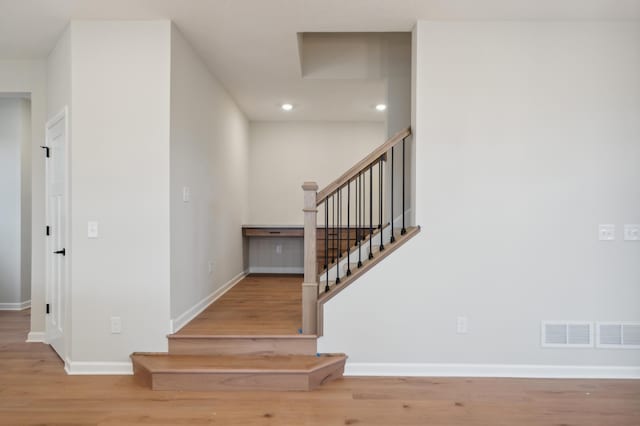 stairway with wood finished floors, baseboards, and recessed lighting