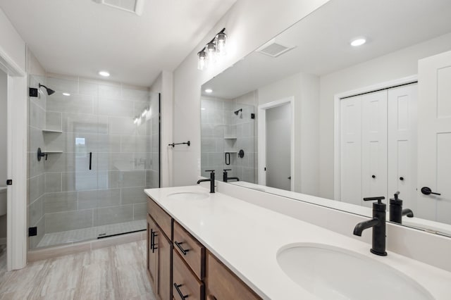 bathroom featuring a stall shower, double vanity, and recessed lighting