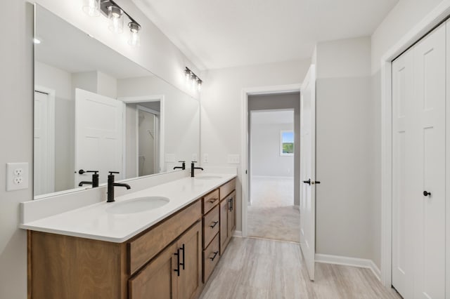 bathroom with double vanity, wood finished floors, and baseboards