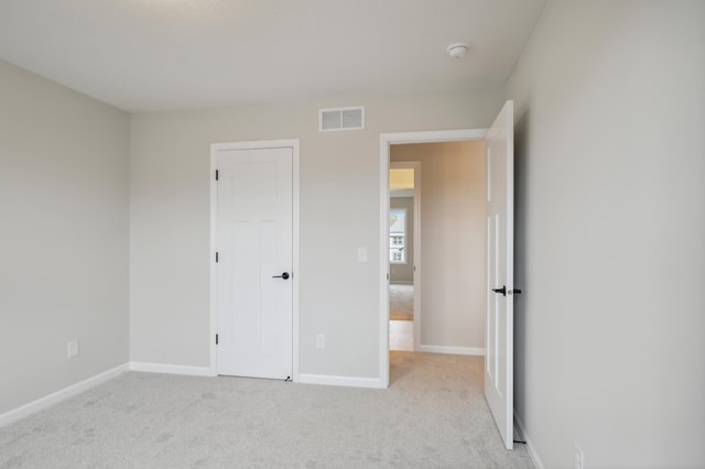 unfurnished bedroom featuring light carpet and baseboards