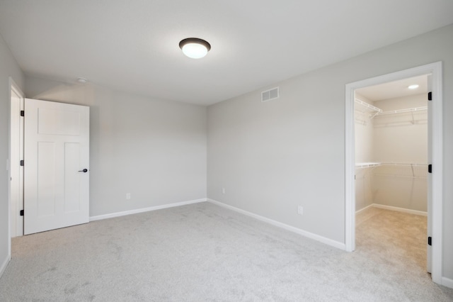 unfurnished bedroom featuring carpet, a walk in closet, baseboards, and a closet