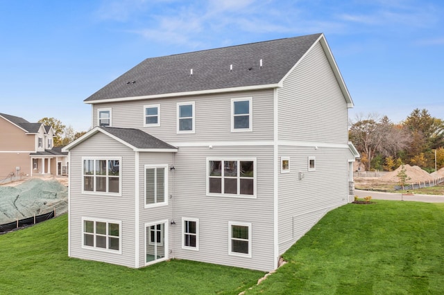 back of property featuring a lawn and a shingled roof