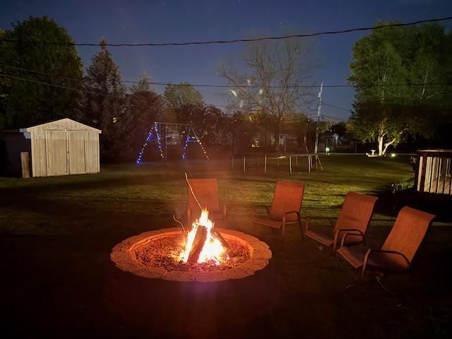 726 17th St NE, Owatonna, MN 55060 - view of patio / terrace with a fire pit, a storage unit, and an outbuilding