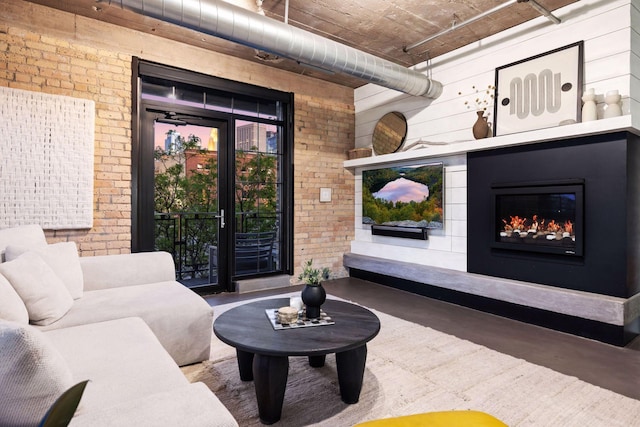 interior space featuring finished concrete flooring, brick wall, and a glass covered fireplace