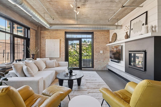 living area with brick wall, concrete floors, and track lighting