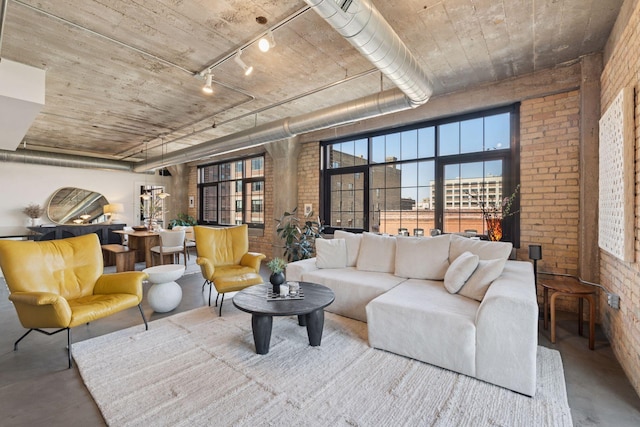 living room with brick wall, finished concrete flooring, and rail lighting