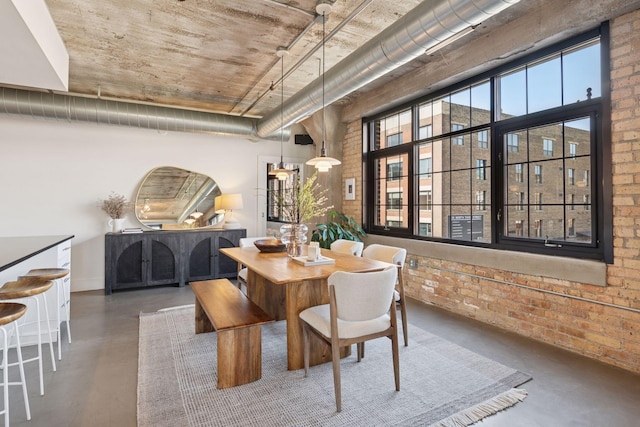 dining room with finished concrete flooring and brick wall