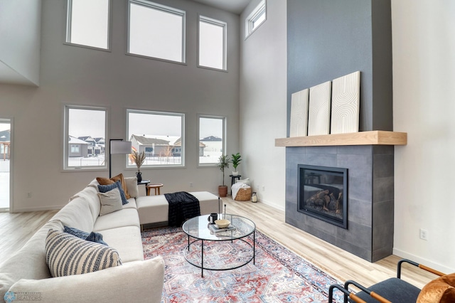 living area with wood finished floors, a fireplace, a high ceiling, and baseboards
