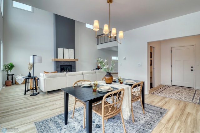 dining space with light wood-type flooring, a chandelier, a fireplace, and baseboards