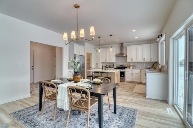 dining room with light wood finished floors, recessed lighting, a chandelier, and baseboards
