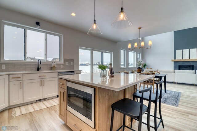 kitchen featuring a sink, built in microwave, light wood-style flooring, light countertops, and tasteful backsplash